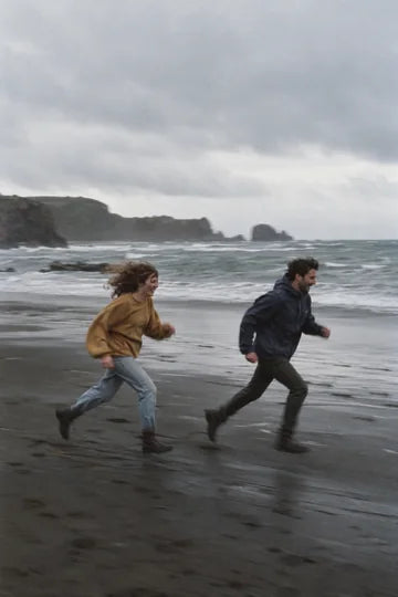 Deux amis courant sur une plage au vent